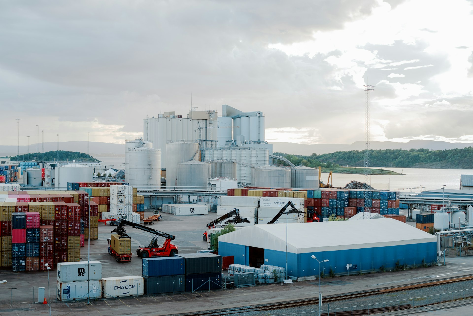 a large industrial area with a large body of water in the background